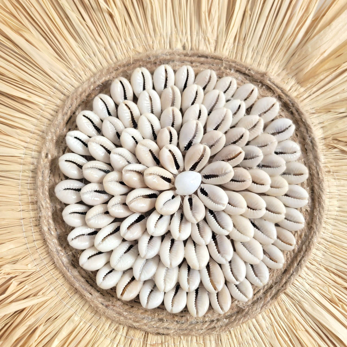 Seashell & Raffia & feathers juju hat Wall Decor - Boho featuring a cluster of shells on a straw background.