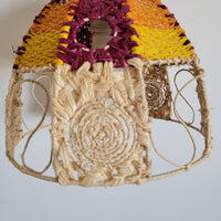 Handwoven raffia lamp shade showcasing vibrant colors of orange, yellow, and purple in a boho chic design.