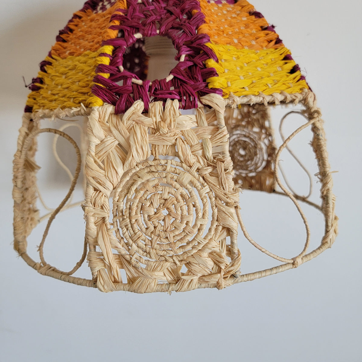 Handwoven raffia lamp shade showcasing vibrant colors and intricate patterns, perfect for artisanal boho chic lighting.