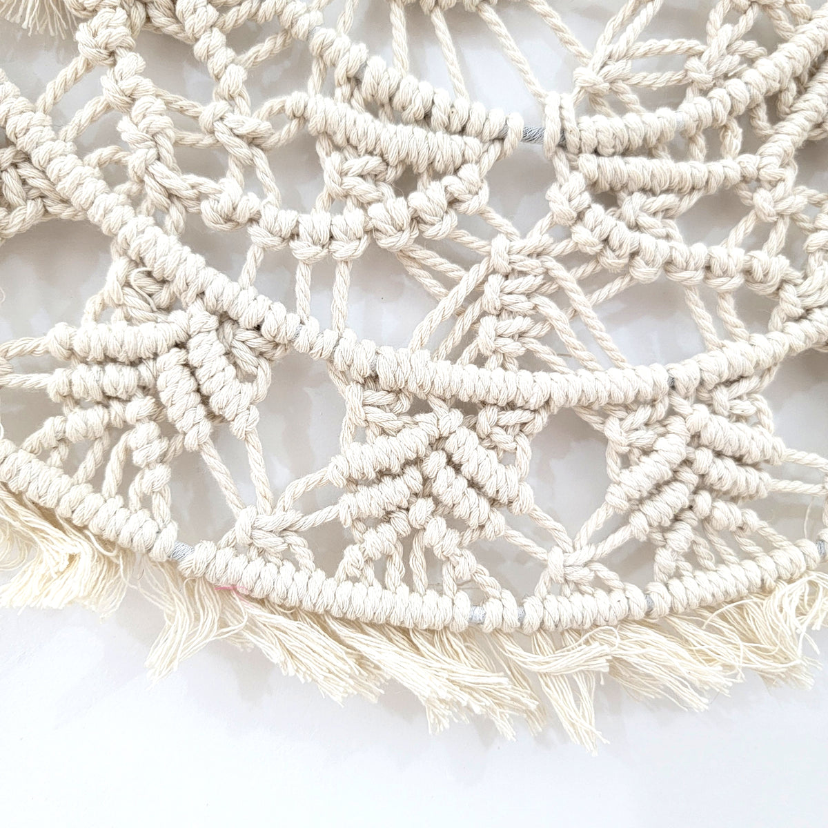 Detail of a circular woven Bohemian macrame wall hanging with intricate patterns and fringes.