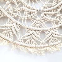 Detail of a circular woven Bohemian macrame wall hanging with intricate patterns and fringes.