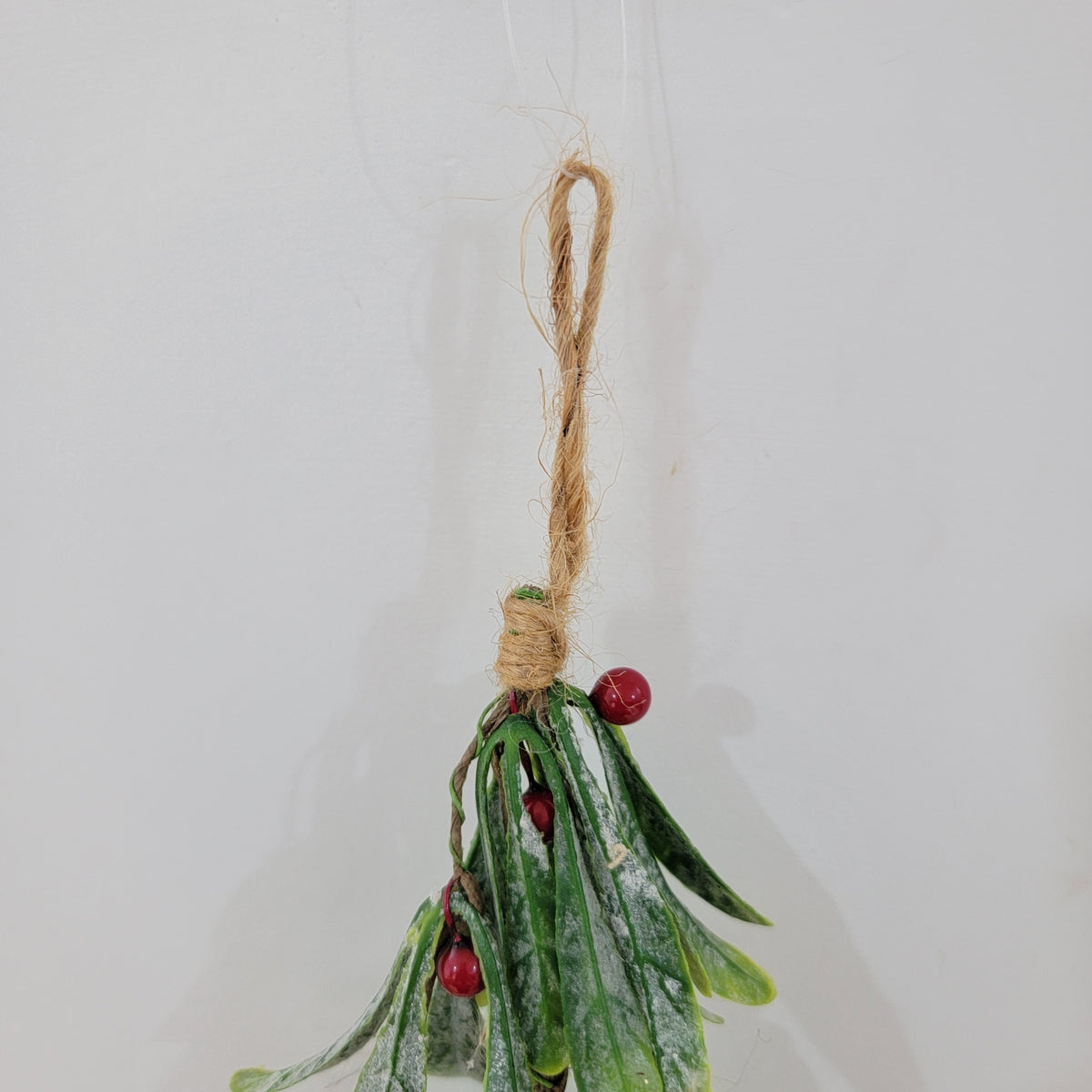 Artificial Christmas mistletoe hanging decoration with red berries and hemp rope.