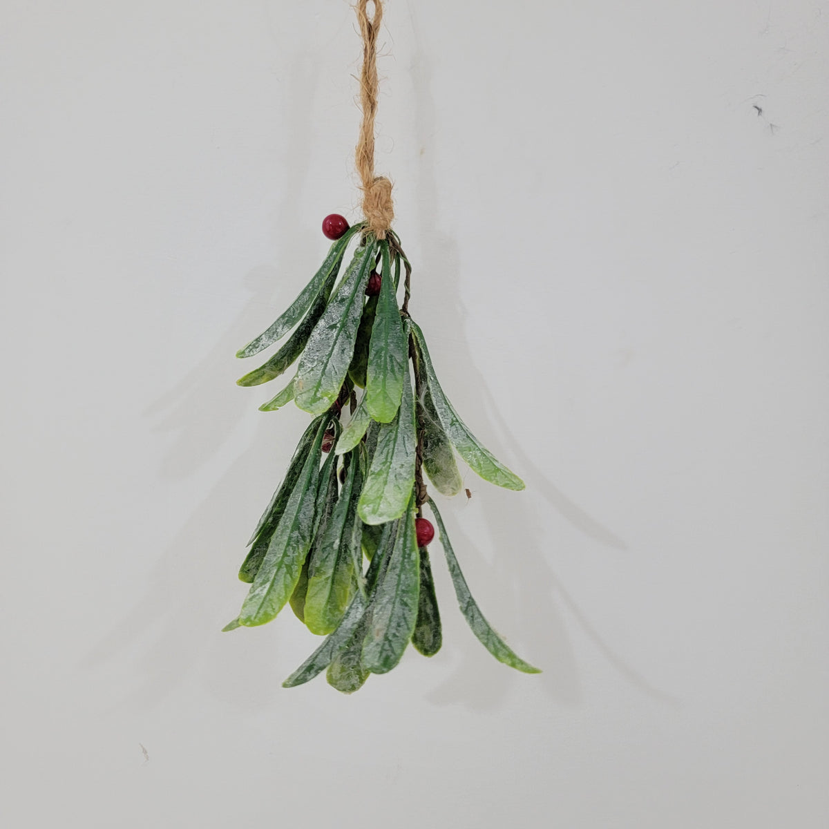 Artificial Christmas mistletoe hanging decoration with red berries and hemp rope.