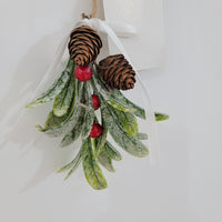 Artificial mistletoe decoration with green leaves and white, gold berries, tied with a ribbon, perfect for holiday decor.