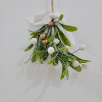 Artificial mistletoe decoration with green leaves and white, gold berries, tied with a ribbon, perfect for holiday decor.