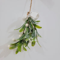 Artificial mistletoe decoration with green leaves and white berries, tied with a twine bow for festive wall decor.