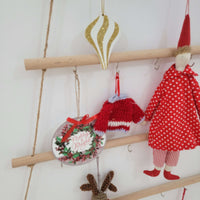 Rustic wooden christmas tree wall mounted hook rack displaying colorful Christmas ornaments and decorations.